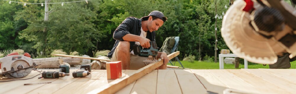 homeowner cutting a piece of wood on their deck