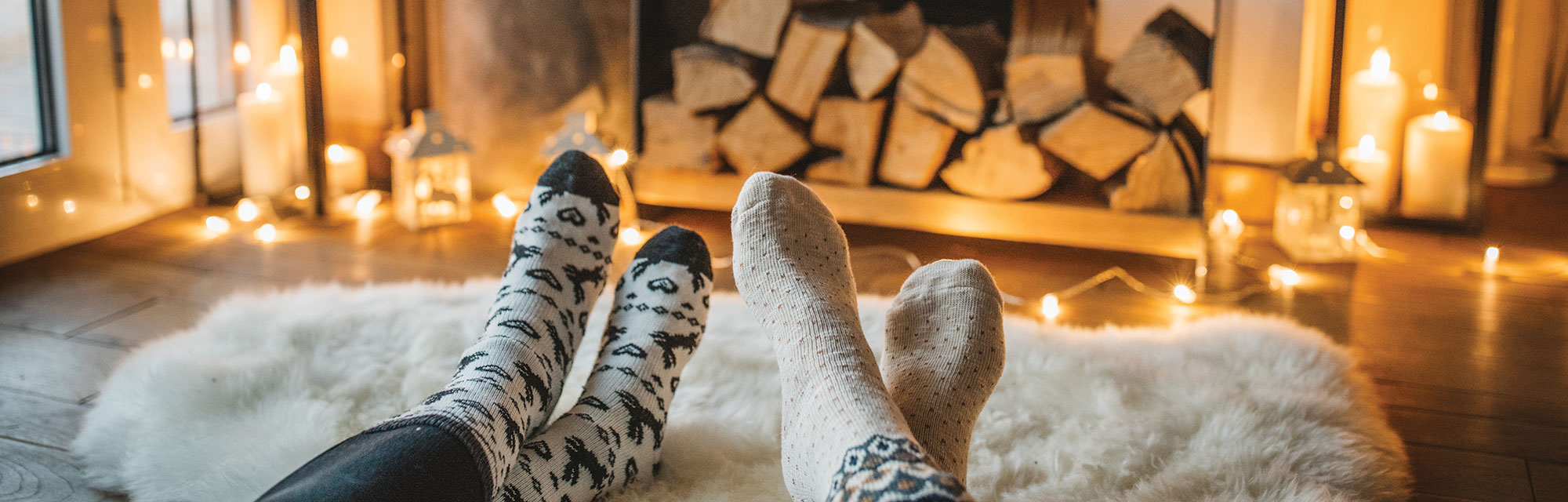 close up of two homeowners' feet wearing socks and resting on a cozy rug in front of a fireplace