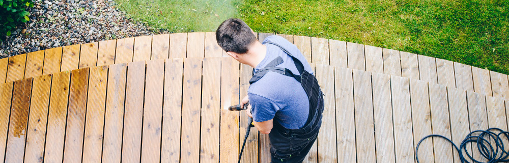 homeowner cleaning deck outside of their home to prepare for summer
