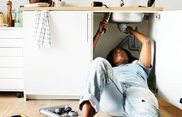 homeowner making repairs under the kitchen sink